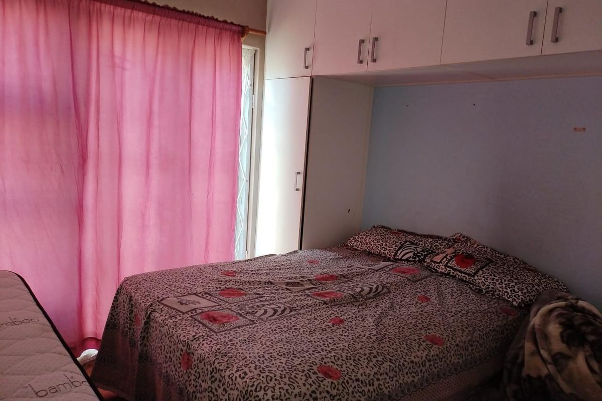 Bedroom featuring built-in cupboards with overhead storage units and access to a patio area through a security gate.