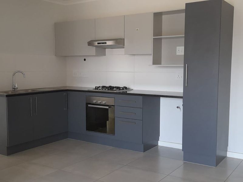 Modern kitchen featuring grey cabinetry, gas hob, built-in oven, extractor fan, and tiled flooring in an open-plan layout.