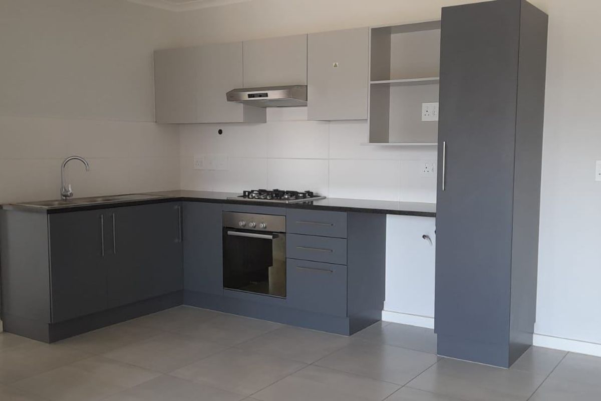Modern kitchen featuring grey cabinetry, gas hob, built-in oven, extractor fan, and tiled flooring in an open-plan layout.