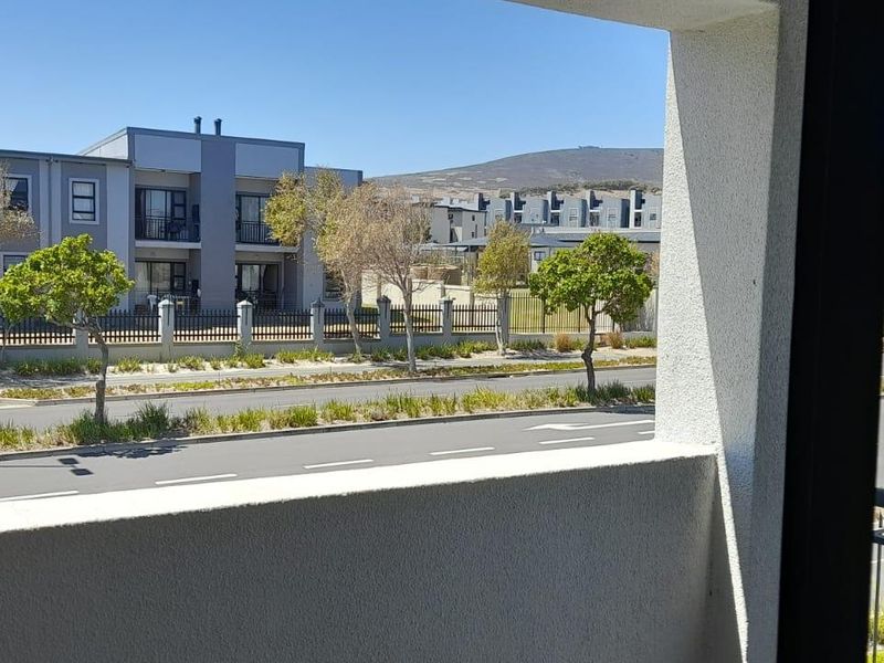 A view from a balcony overlooking a suburban street and neighbouring apartment complex.