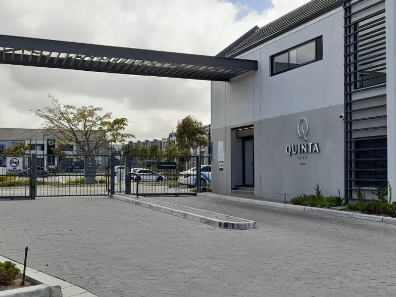 The secure entrance to Quinta Estate featuring a modern gatehouse, paved driveway, and controlled access security infrastructure.