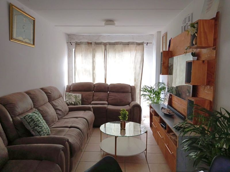 A cozy living room featuring tiled flooring and a neutral color palette, providing a comfortable space for relaxation.