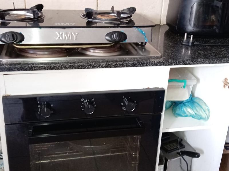 Kitchen area featuring a built-in oven, gas hob, granite countertops, and tiled backsplash, with visible wear to the base cabinetry.