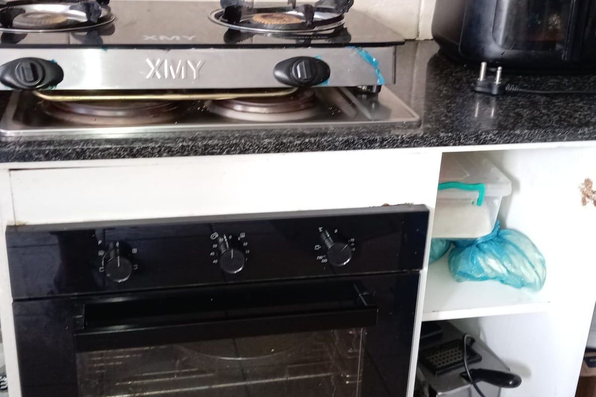 Kitchen area featuring a built-in oven, gas hob, granite countertops, and tiled backsplash, with visible wear to the base cabinetry.