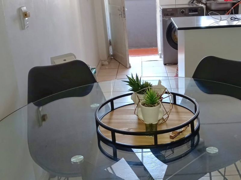 Open plan dining area leading into a functional kitchen with tiled flooring and direct access to an exterior balcony.