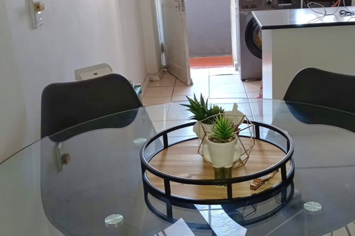 Open plan dining area leading into a functional kitchen with tiled flooring and direct access to an exterior balcony.