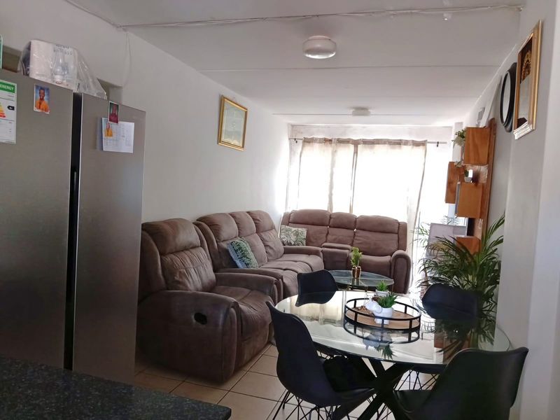 An open-plan living and dining area featuring tiled flooring, neutral walls, and a granite countertop, providing a functional space for daily living.