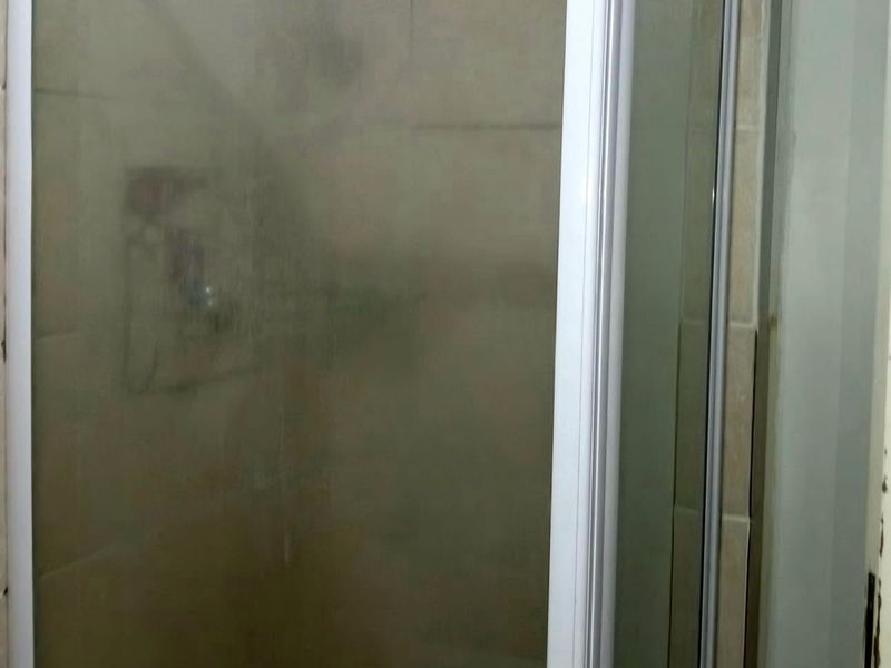 A bathroom featuring a shower enclosure with tiled walls and a fixed shower head.