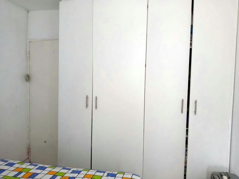 A bedroom featuring a large, white built-in wardrobe with modern handles, providing ample storage space.