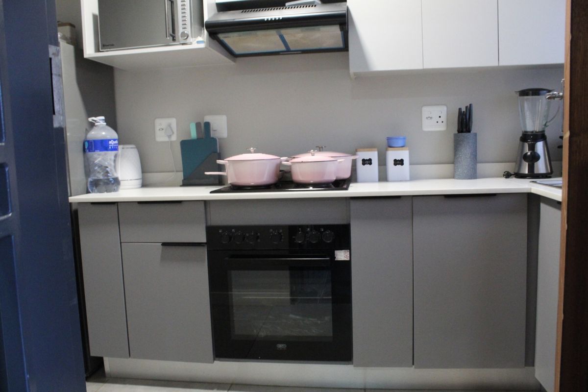 Modern kitchen featuring grey cabinetry, white countertops, a built-in oven, and an extractor fan, providing a clean and functional cooking space.
