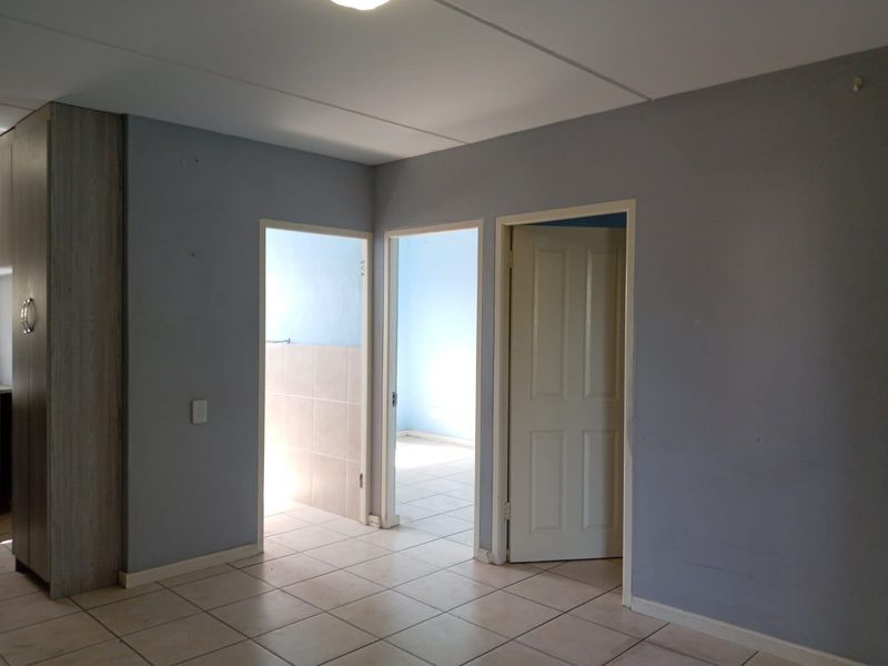 A vacant hallway featuring tiled flooring and access to adjacent rooms, with neutral wall finishes and built-in cabinetry.