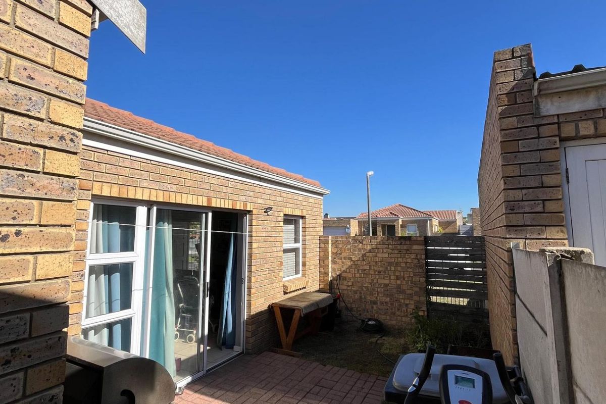 A private rear courtyard featuring paved flooring, brick boundary walls, and sliding door access to the main living area.