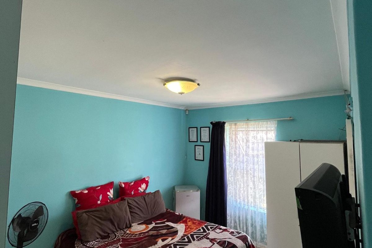 A bedroom featuring tiled flooring, a ceiling-mounted light fixture, and a window with curtain rails.