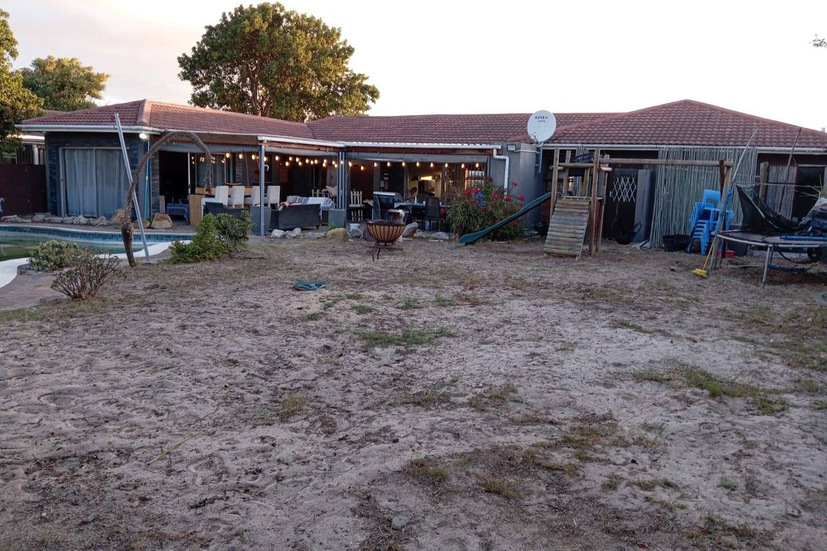 Rear view of the house featuring a covered patio area, swimming pool, and a large backyard space.