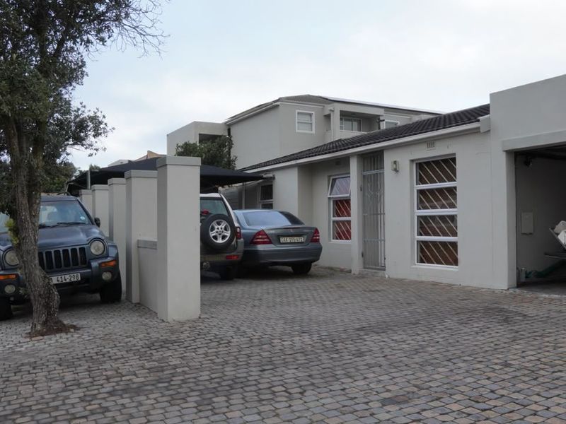 Front exterior view of the property featuring a paved driveway, integrated garage, and secure entrance with security gates and bars.