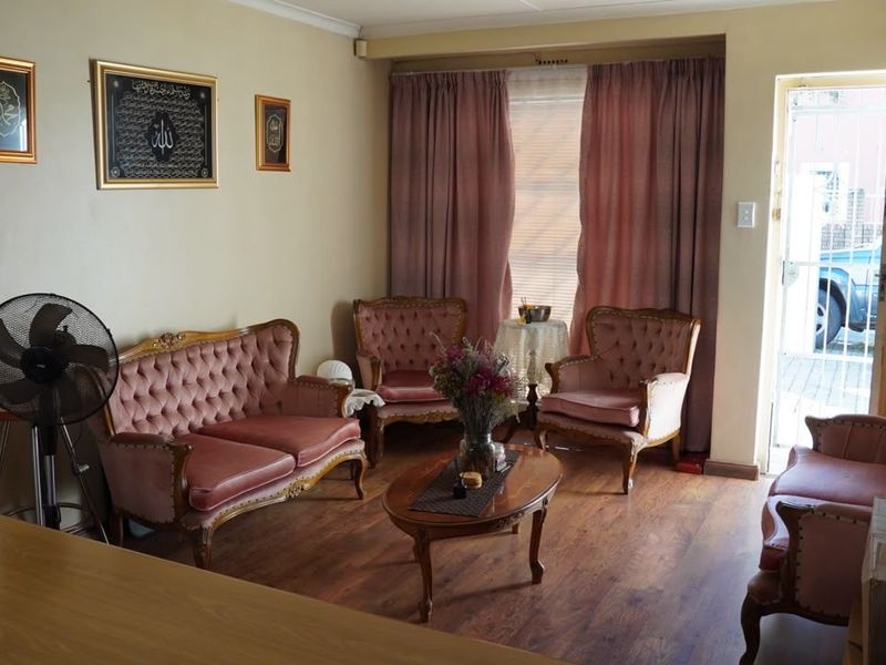 A comfortable living room featuring laminate flooring, coved ceilings, and direct access to the exterior through a security gate.