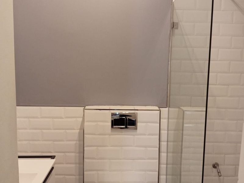 Modern bathroom featuring a wall-hung toilet with concealed cistern, subway tile backsplash, and a glass-enclosed shower area.