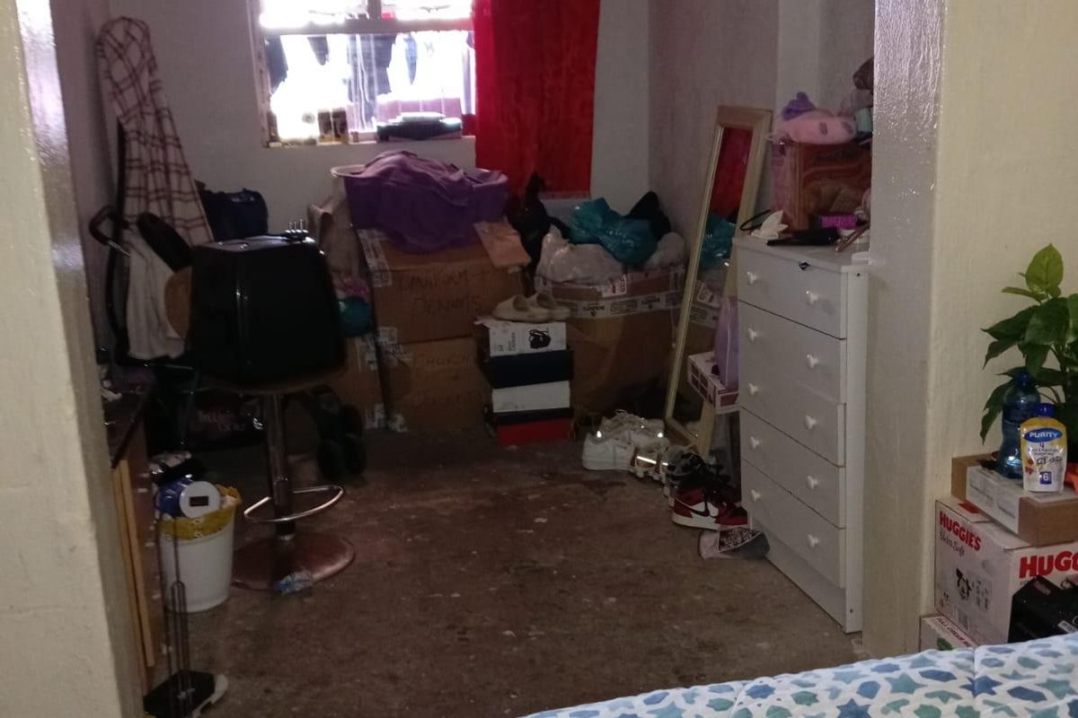 A bedroom space requiring significant maintenance and renovation, featuring visible wear on the ceiling and flooring surfaces.