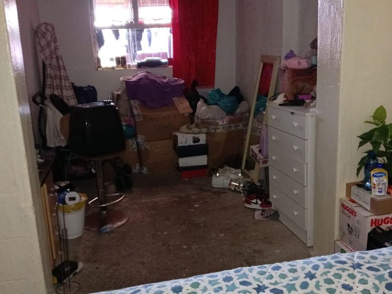 A bedroom space requiring significant maintenance and renovation, featuring visible wear on the ceiling and flooring surfaces.