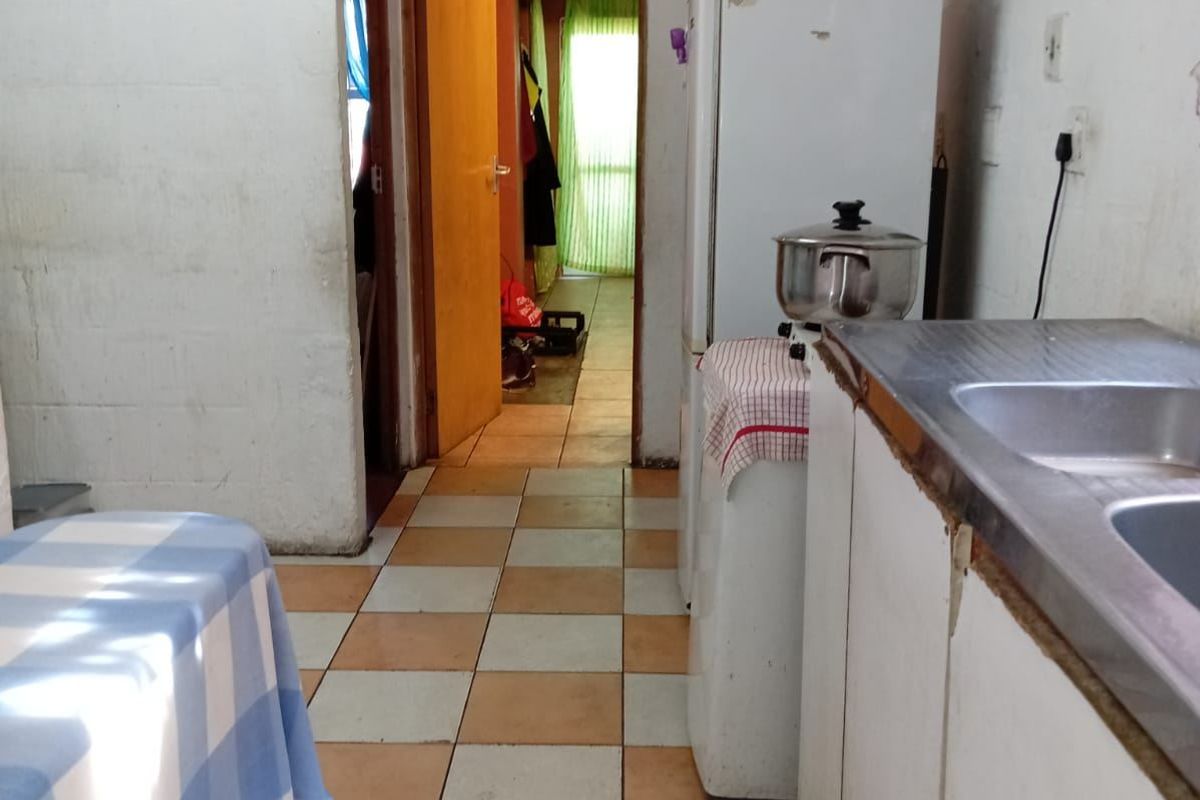 A dated kitchen area featuring tiled flooring, basic cabinetry, and a stainless steel sink, requiring cosmetic updates to improve its overall appeal.