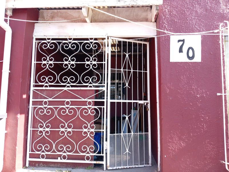 Front entrance of the property featuring a decorative white security gate and painted masonry exterior wall.