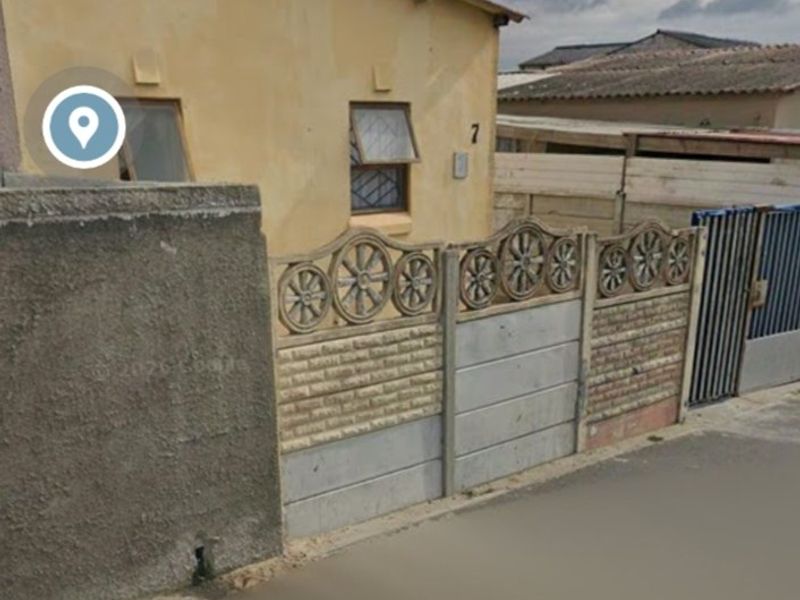 Front exterior view of a residential property featuring a decorative precast concrete boundary wall, metal gate, and weathered facade.