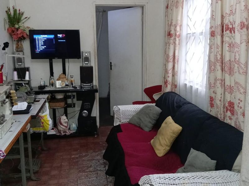 A living room area featuring tiled flooring and access to an adjacent room, requiring cosmetic updates to improve the overall aesthetic.