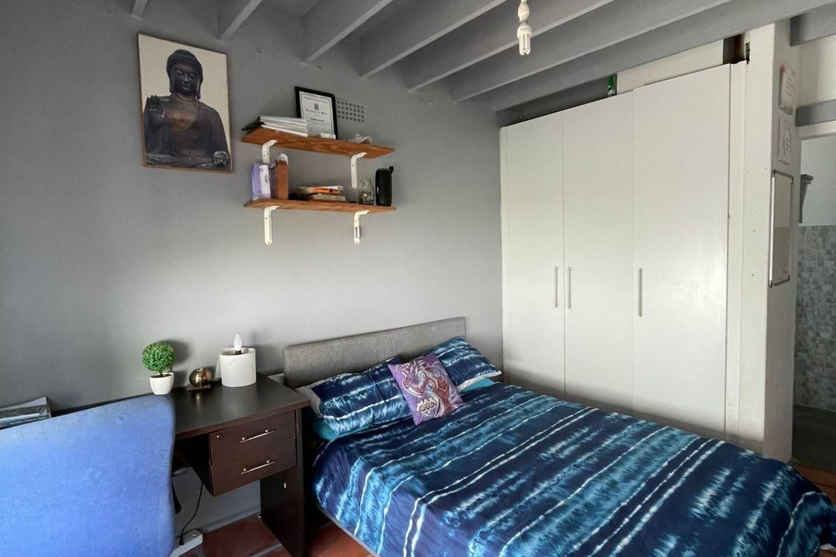 A bedroom featuring exposed ceiling beams, terracotta floor tiles, and a built-in wardrobe, offering a functional space with potential for aesthetic updates.