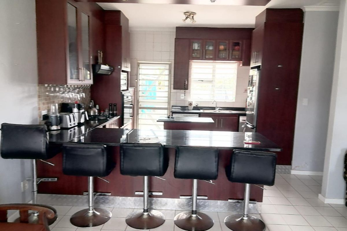A functional kitchen featuring dark wood cabinetry, granite countertops, a breakfast bar, and built-in appliances, offering a classic layout with ample storage space.