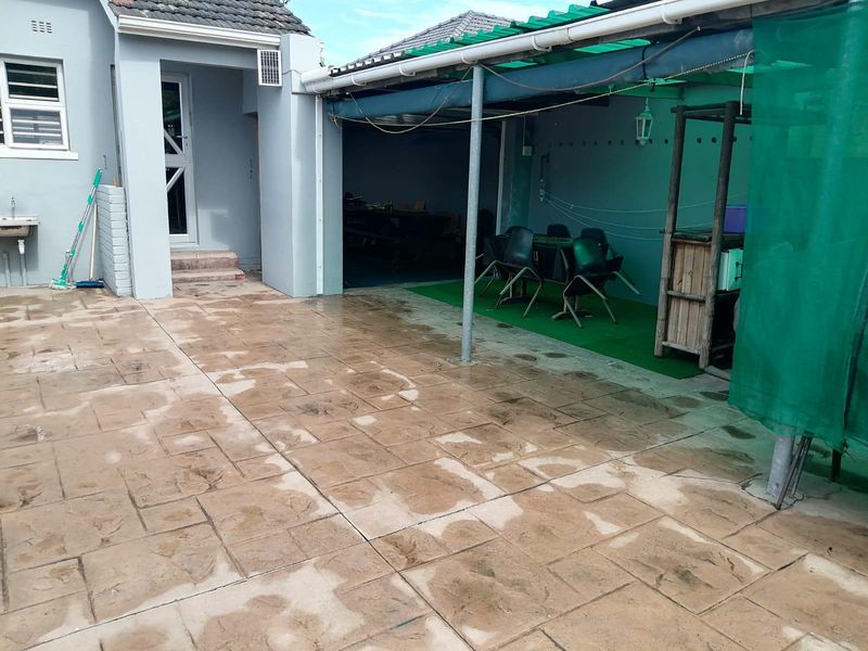 A paved outdoor patio area featuring a covered section, external wash basin, and direct access to the main house structure.