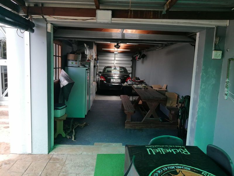 A functional garage space featuring exposed timber ceiling beams and concrete flooring, currently utilized for storage and parking.