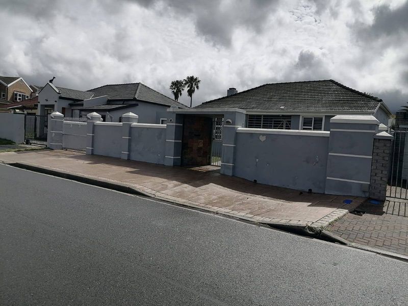 Front exterior view of the property featuring a perimeter wall, tiled roof, and paved driveway entrance.
