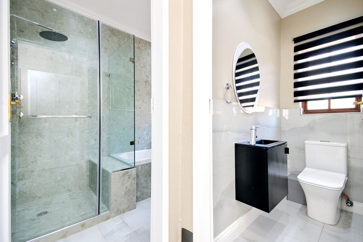 Modern bathroom featuring a glass-enclosed shower, built-in bathtub, wall-mounted vanity, and contemporary tiling throughout.