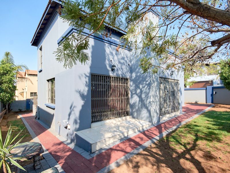 Rear view of the property featuring a paved walkway, tiled patio area, and security gates on the sliding doors.