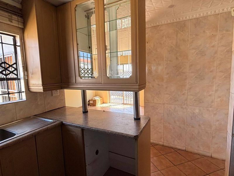 A dated kitchen featuring built-in cabinetry, laminate countertops, and tiled finishes, offering a functional layout ready for modern renovation and cosmetic updates.