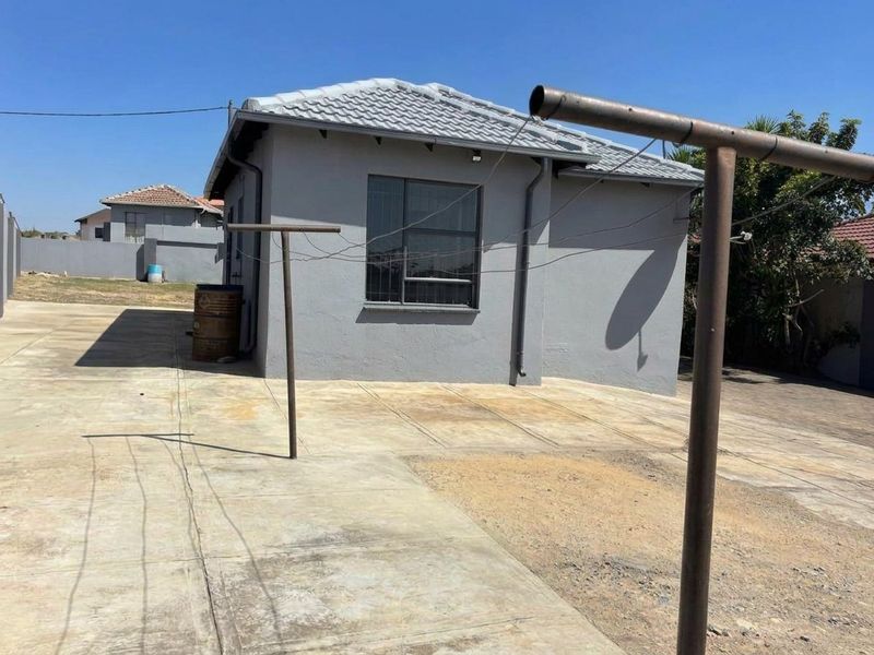 Rear view of the property featuring a paved yard area, tiled roof, and exterior wall finishes.