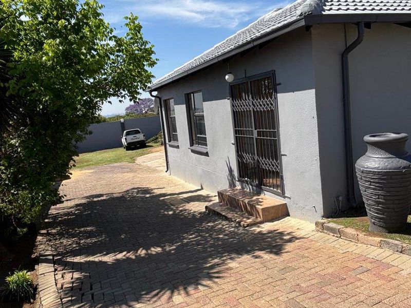 Rear exterior view of the property featuring a paved driveway, security gate, and tiled roof structure.