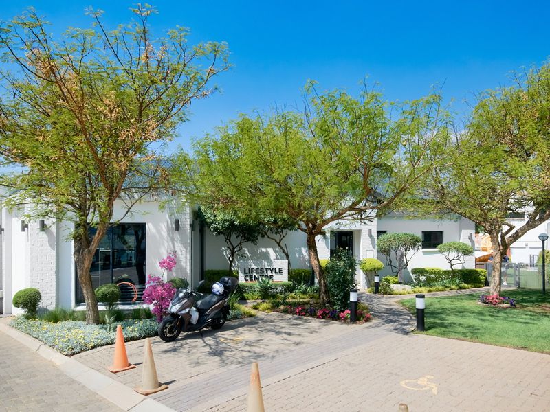 A well-maintained exterior view of the apartment complex lifestyle centre, featuring a paved entrance, landscaped gardens, and modern building facade.