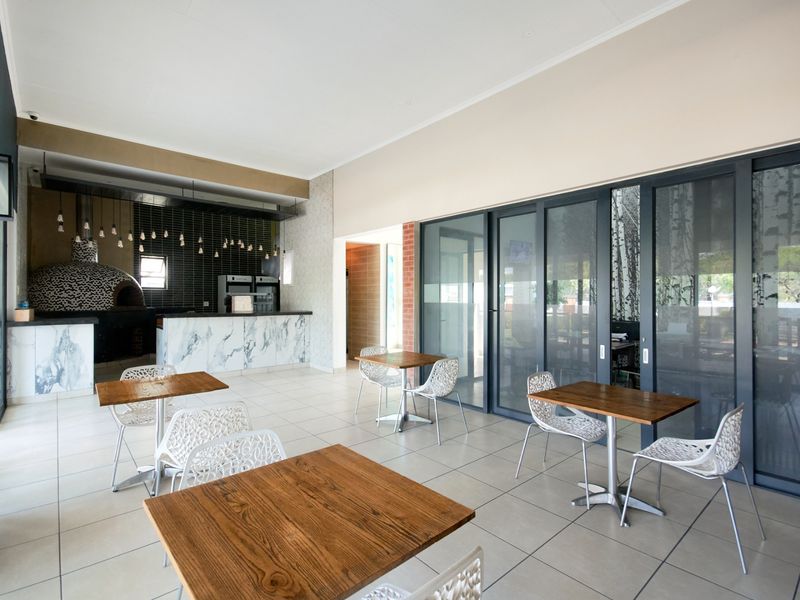 Spacious covered patio featuring a built-in pizza oven, marble-look prep area, and large sliding glass doors connecting to the interior living space.
