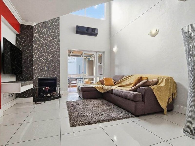 Spacious living room featuring high vaulted ceilings, tiled flooring, a modern fireplace, and a split-system air conditioner with access to an outdoor area.