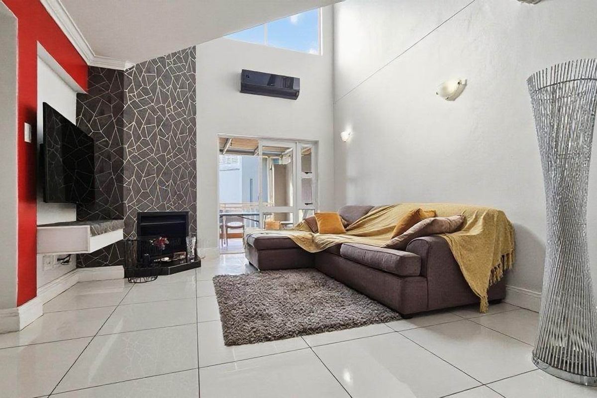 Spacious living room featuring high vaulted ceilings, tiled flooring, a modern fireplace, and a split-system air conditioner with access to an outdoor area.