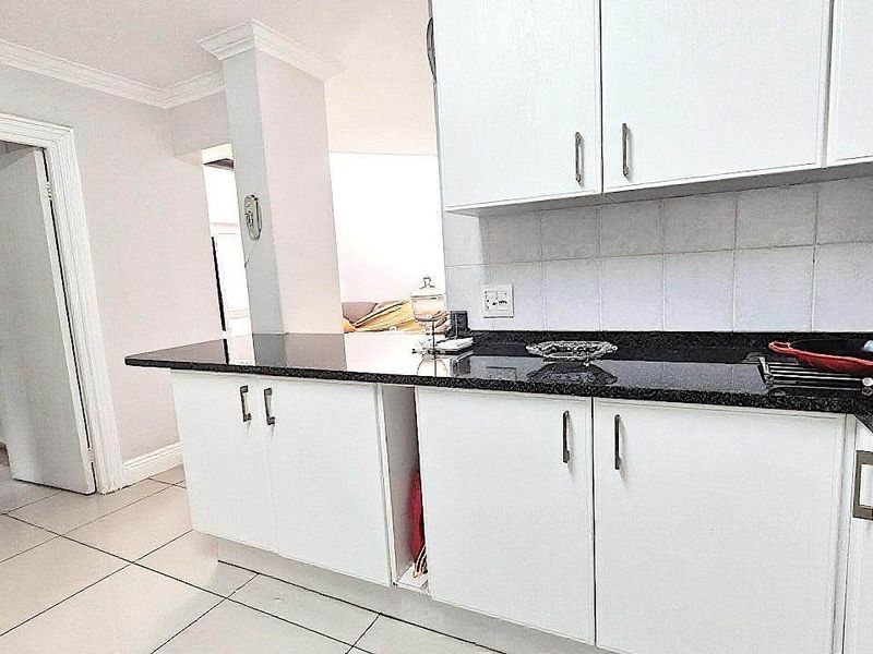 A functional kitchen featuring white cabinetry, dark granite countertops, and tiled flooring, providing a clean and practical workspace.