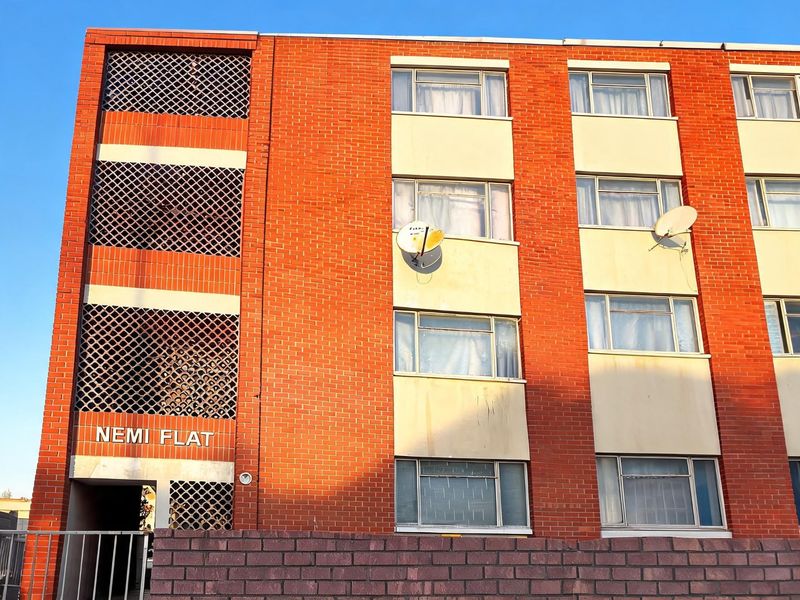 Front elevation of Nemi Flat apartment building featuring red brick facade, lattice screening, and multiple window units.