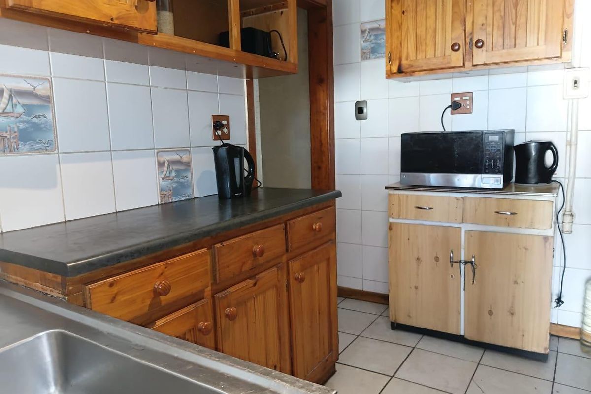 A dated kitchen featuring pine cabinetry, laminate countertops, and ceramic tiling, offering a functional layout ready for modern renovation and aesthetic updates.