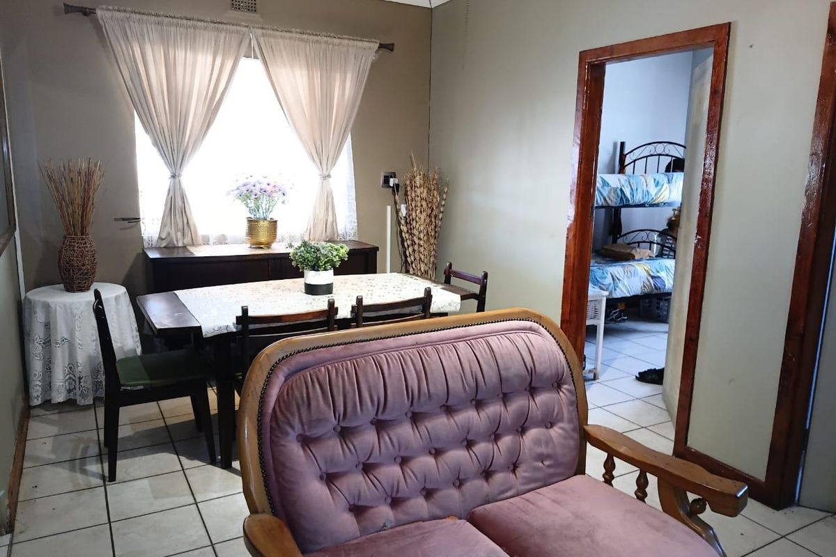 A living area featuring ceramic floor tiles, cove cornicing, and a timber door frame leading to an adjacent bedroom.