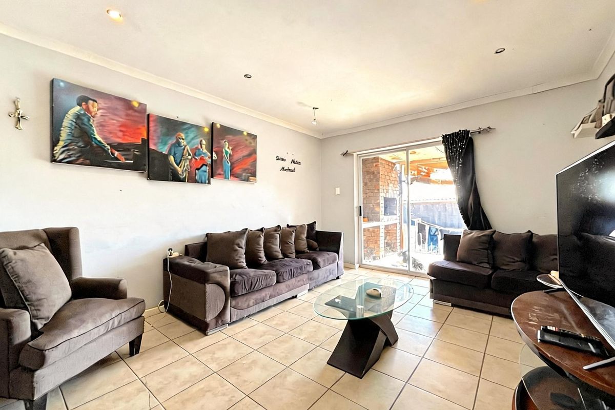 A living room featuring ceramic tiled flooring, recessed downlighting, and a sliding glass door providing access to the outdoor area.