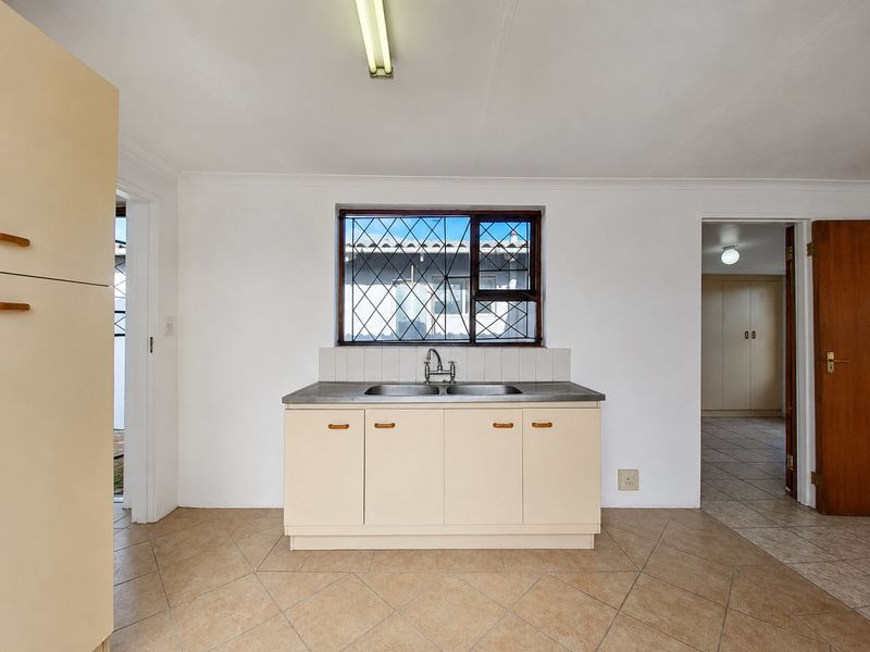 A functional kitchen area featuring a stainless steel double sink, laminate cabinetry, and tiled flooring, offering a blank canvas for potential renovation.
