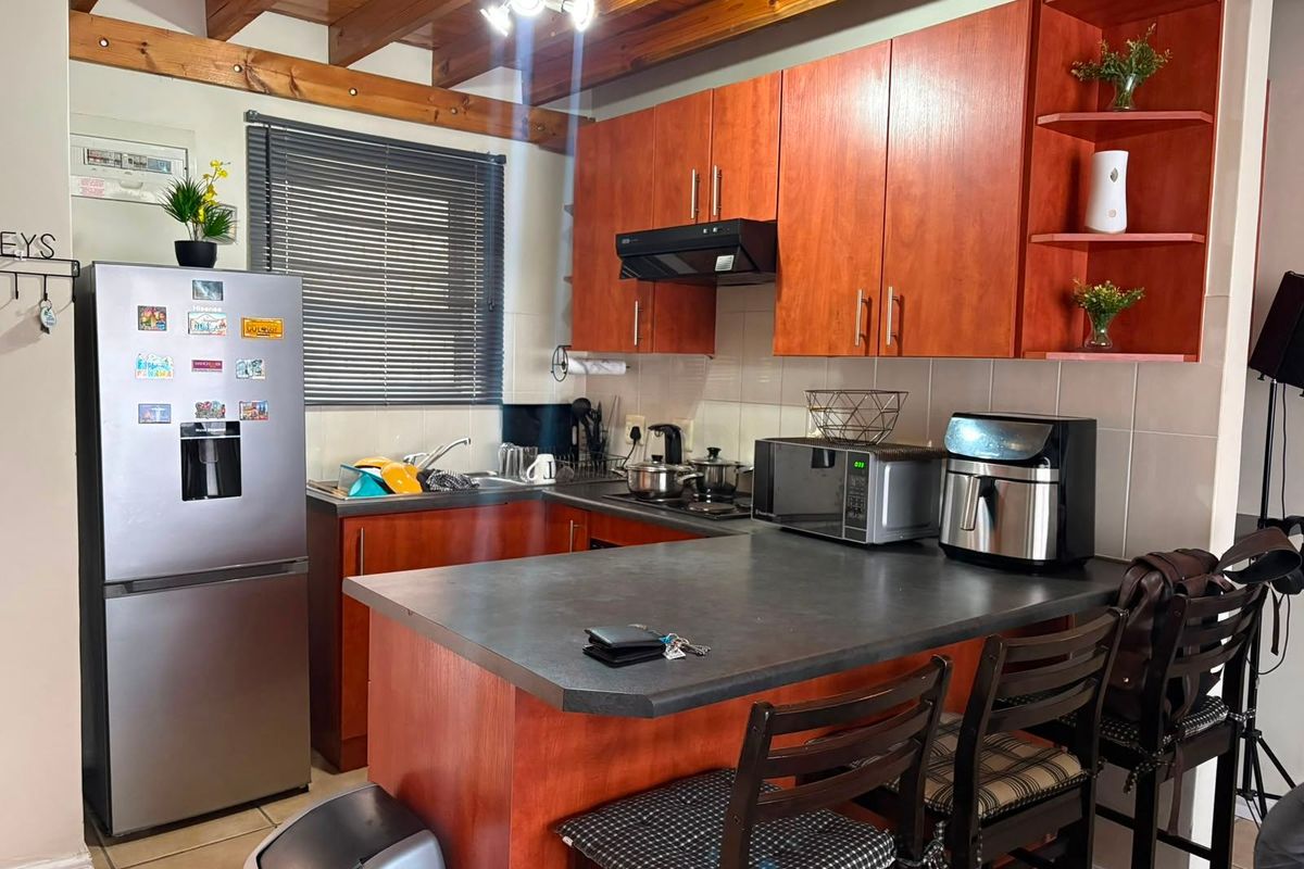 A functional kitchen featuring warm-toned cabinetry, a breakfast bar, and exposed timber ceiling beams, providing a cozy and practical cooking space.