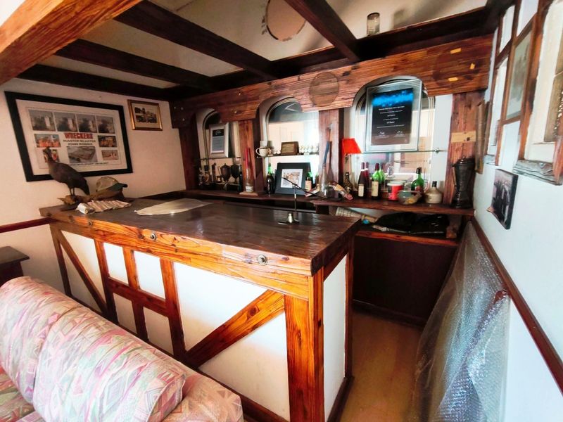 A rustic-style built-in timber bar area featuring exposed ceiling beams and mirrored back shelving, offering a classic pub-style aesthetic.