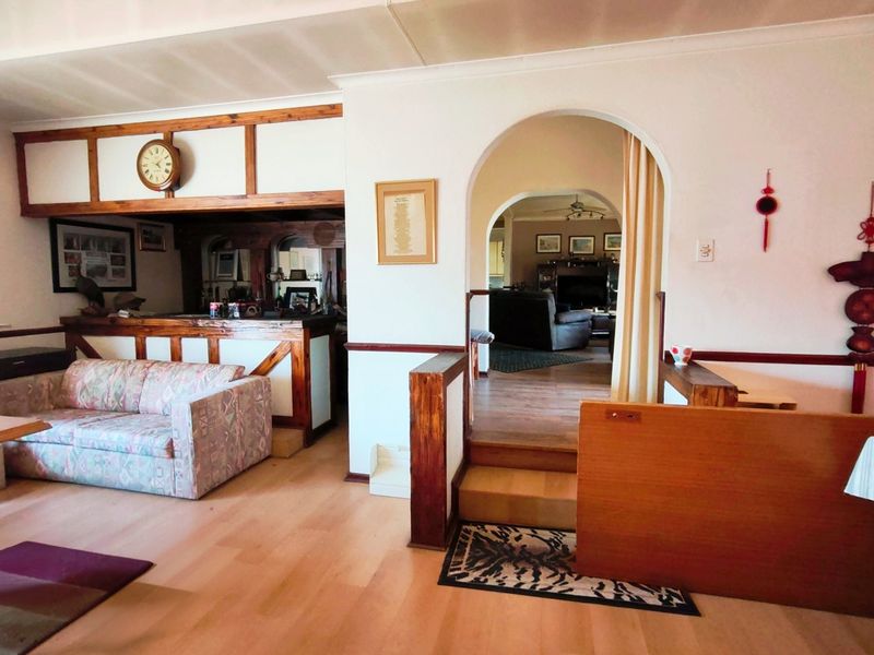 A multi-level living area featuring a built-in bar, timber accents, and an arched transition leading to an adjacent living space.